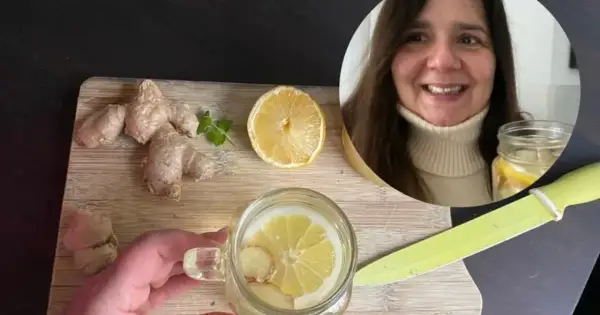Kobieta przygotowuje orzeźwiającą wodę z cytryną i imbirem. Na desce leżą świeże korzenie imbiru i plaster cytryny.