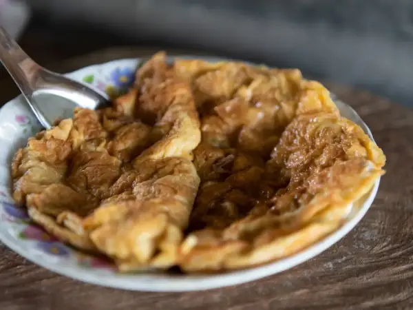 Puszysty omlet na słodko, lekko zarumieniony, podany na talerzyku z kwiatowym wzorem. Idealny na słodkie śniadanie.
