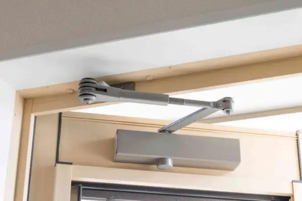 Mechanizm samozamykacza drzwi, zamontowany na futrynie, zapewnia płynną regulację domykania.