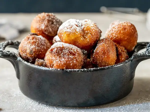 Puszyste paczki z serka homo, posypane cukrem pudrem, kuszą swoim złotym kolorem i apetycznym wyglądem.