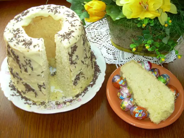 Babka gotowana przepis: puszyste ciasto z lukrem i posypką, obok kawałek z czekoladowymi jajeczkami.