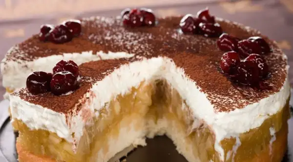 Szarlotka bez pieczenia na herbatnikach z budyniem, udekorowana wiśniami i kakao. Pyszny deser, który zachwyca smakiem.