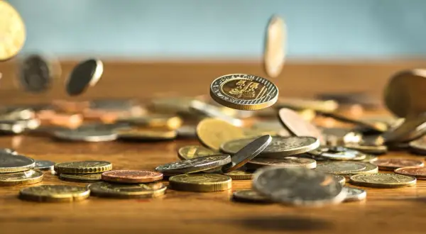 Monety spadają na drewniany blat. Zastanawiasz się, jak wyczyścić monety domowym sposobem? Oto kilka wskazówek.